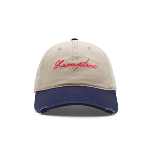 Beige and navy cap with 'Hamptons' embroidery on a white background